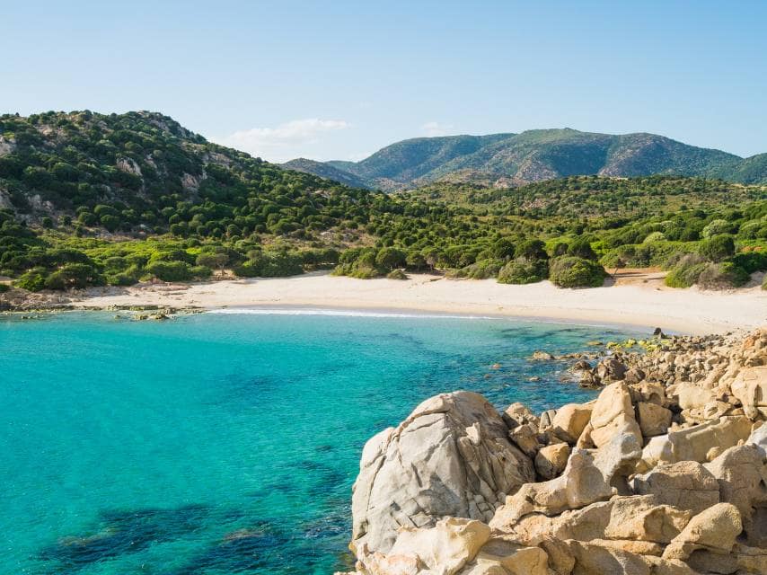 Tranquil Sardinia beach with calm waters, a serene stop on a Mediterranean wellness yacht retreat.