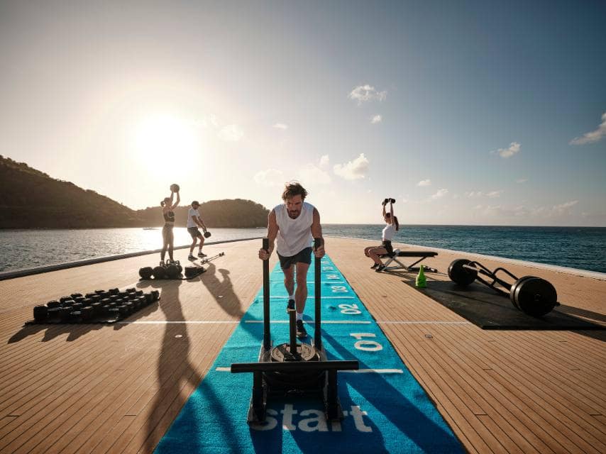 Guests work out with yacht gym equipment during an onboard fitness circuit session, tailored for wellness at sea.