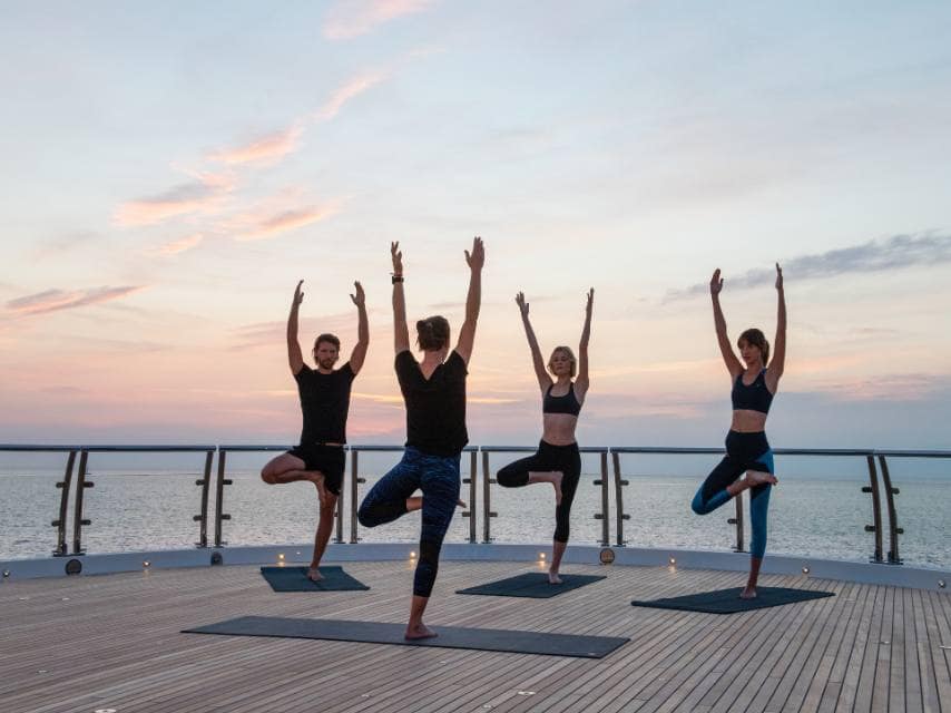 Yoga at sunrise on a superyacht sundeck, offering serenity and ocean views for a mindful wellness retreat.