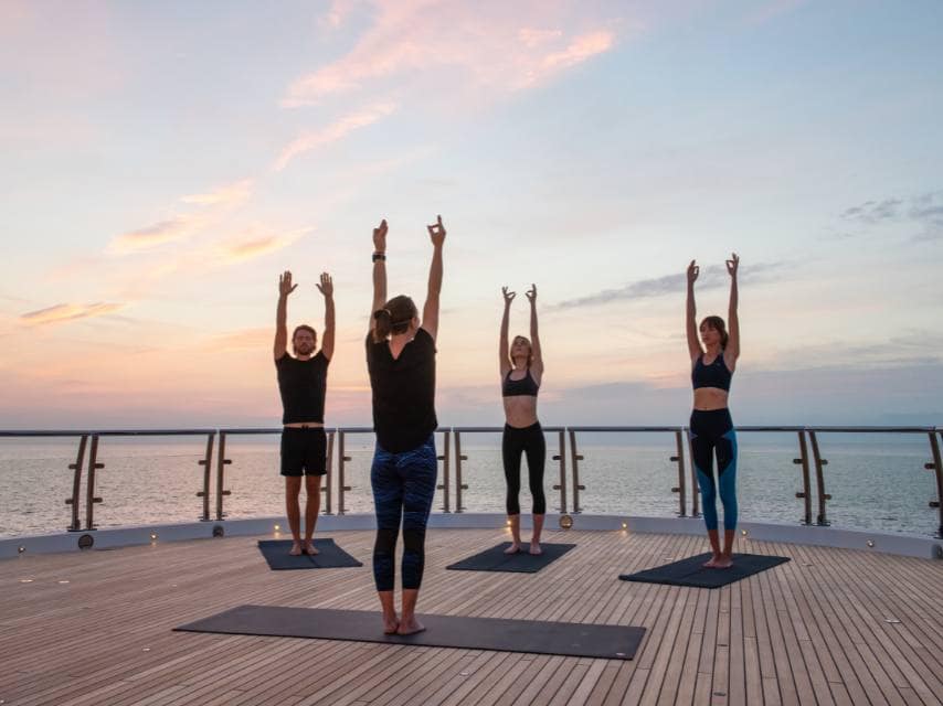 Guests practice yoga between island stops on a luxury Greek mythology yacht charter.