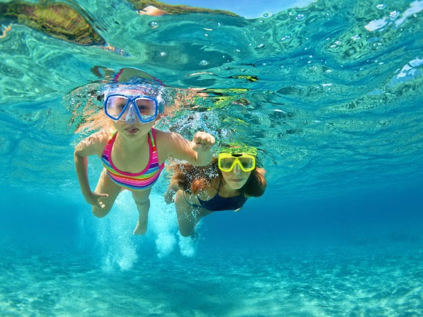 Mother and daughter swim at La Pelosa, Sardinia, a perfect family moment during their Mediterranean sea yacht charter.