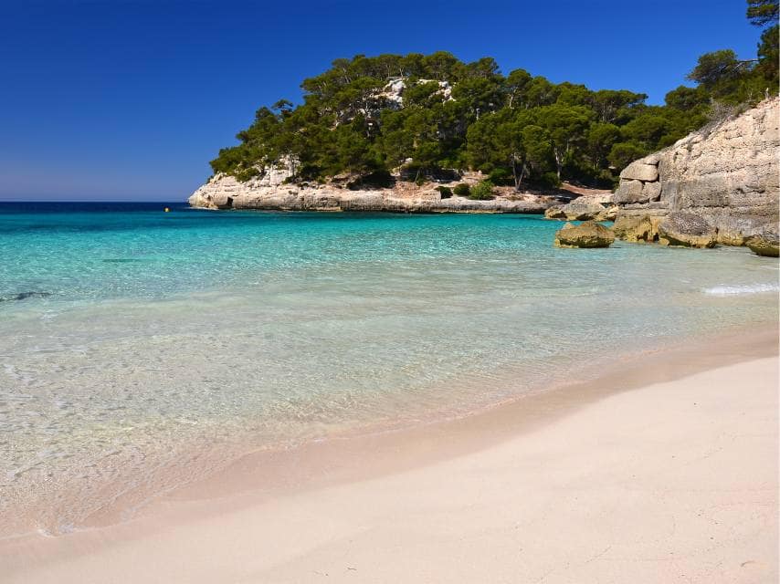 White sand and turquoise waters await at Cala Mitjaneta, a remote beach in Europe perfect for a private yacht anchorage.