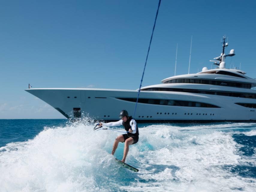 A guest wakeboarding with Sophia Yacht closeby, in Santa Giulia, Corsica — a fun highlight of your Mediterranean superyacht charter.