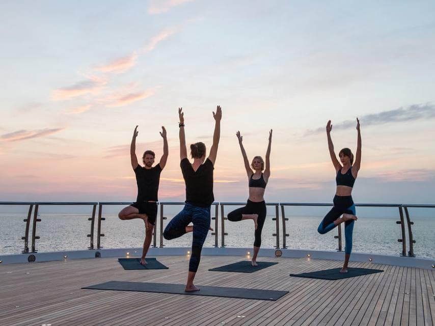 Luxury Caribbean yacht charter guests practice yoga on the sun deck.