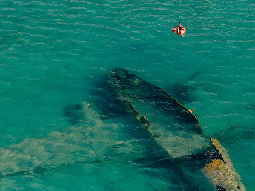 Private islands in the bahamas offer adventurous tender rides; a charter guest relaxes on a floaty near a shallow planewreck