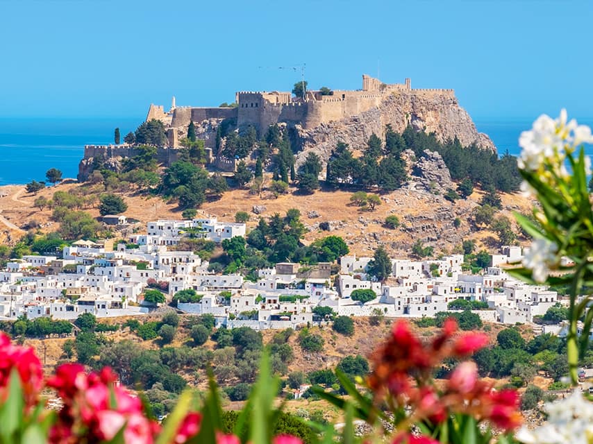 Optimized ALT Text: A Rhodes yacht charter reveals Lindos, its acropolis and castle rising above the whitewashed village below.