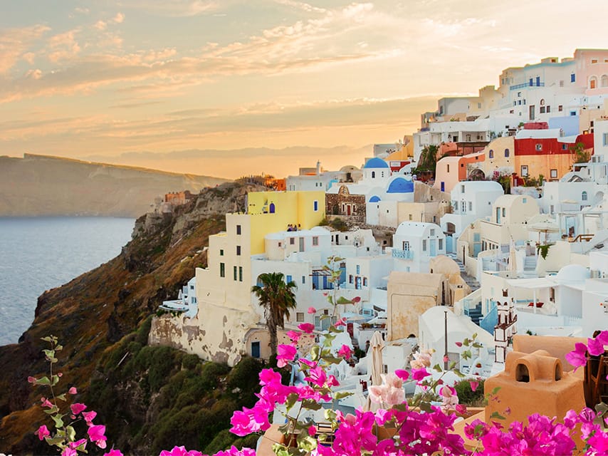 Santorini yacht charter guests can watch sunset over Oia, with blue-domed churches and white cliffside houses.
