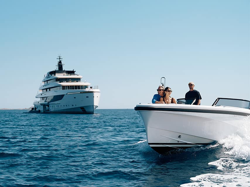 Guests on a Superyacht charter in Greece speed by tender past the 72m Sanlorenzo SILVER FOX in open water.
