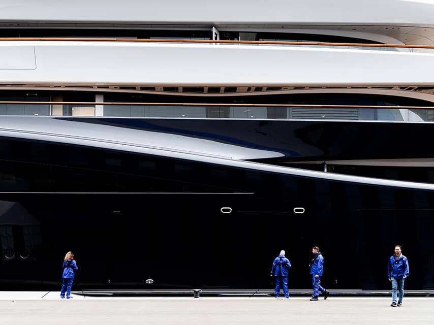 Workers beside the sleek hull of the feadship project 821, the first hydrogen fuel-cell superyacht