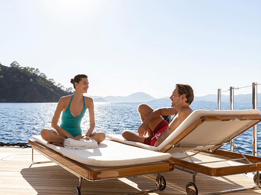 Mykonos yacht charter guests relax on deck aboard the 75m Feadship superyacht ARROW off the Greek coast.