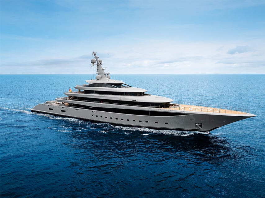 On an Athens yacht charter route, the 102m Lurssen superyacht Nixie cuts across calm blue water under a pale sky.
