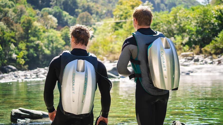 Two friends prepare to dive into the ocean with their new jetpack luxury yacht toys, ready for adventure.