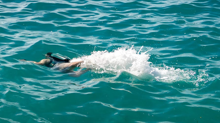 Person swimming in turquoise water with a jetpack, one of the best superyacht toys.