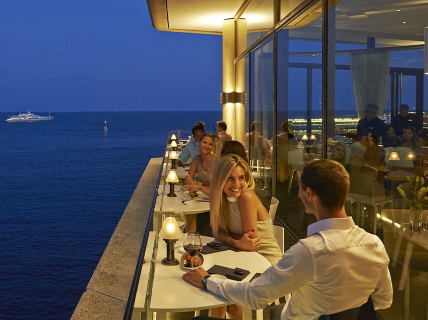 Couple having dinner at a Michelin Star restaurant with a view of luxury superyacht charters