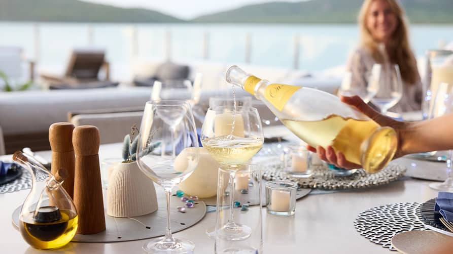 A server pours a glass of chilled white wine from the luxury yacht wine cellar.