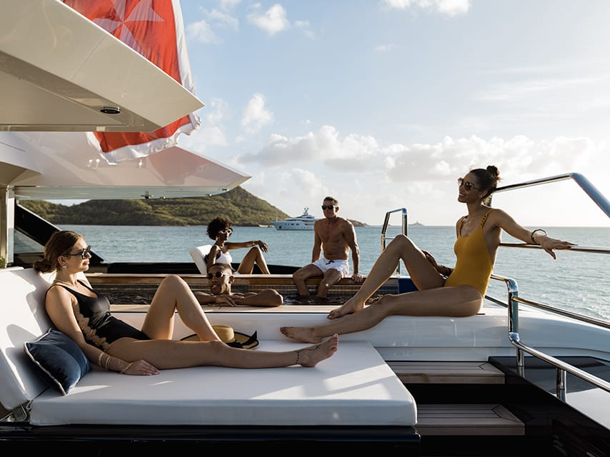 Four friends enjoying the deck of their recently purchased luxury pre-owned yacht.