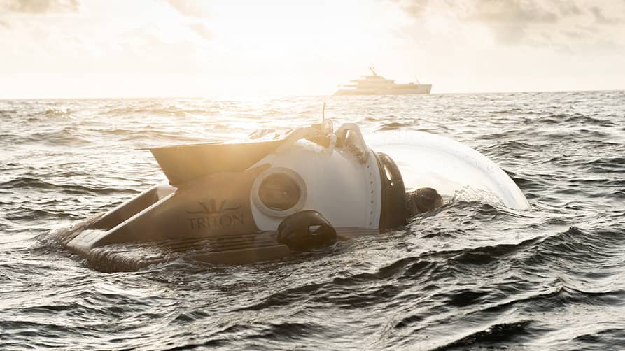 A submarine water toy surfacing in view of a private superyacht