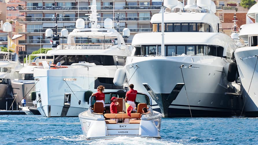 Edmiston staff in a small boat approach 3 superyachts parked at the Monaco Boat Show 2024.