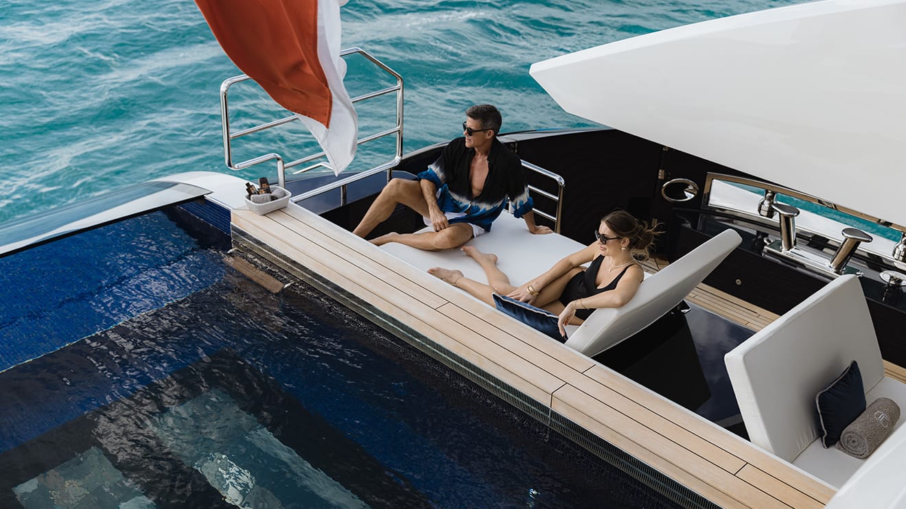 http://A%20couple%20lounging%20by%20the%20pool%20on%20their%20private%20superyacht%20charter.
