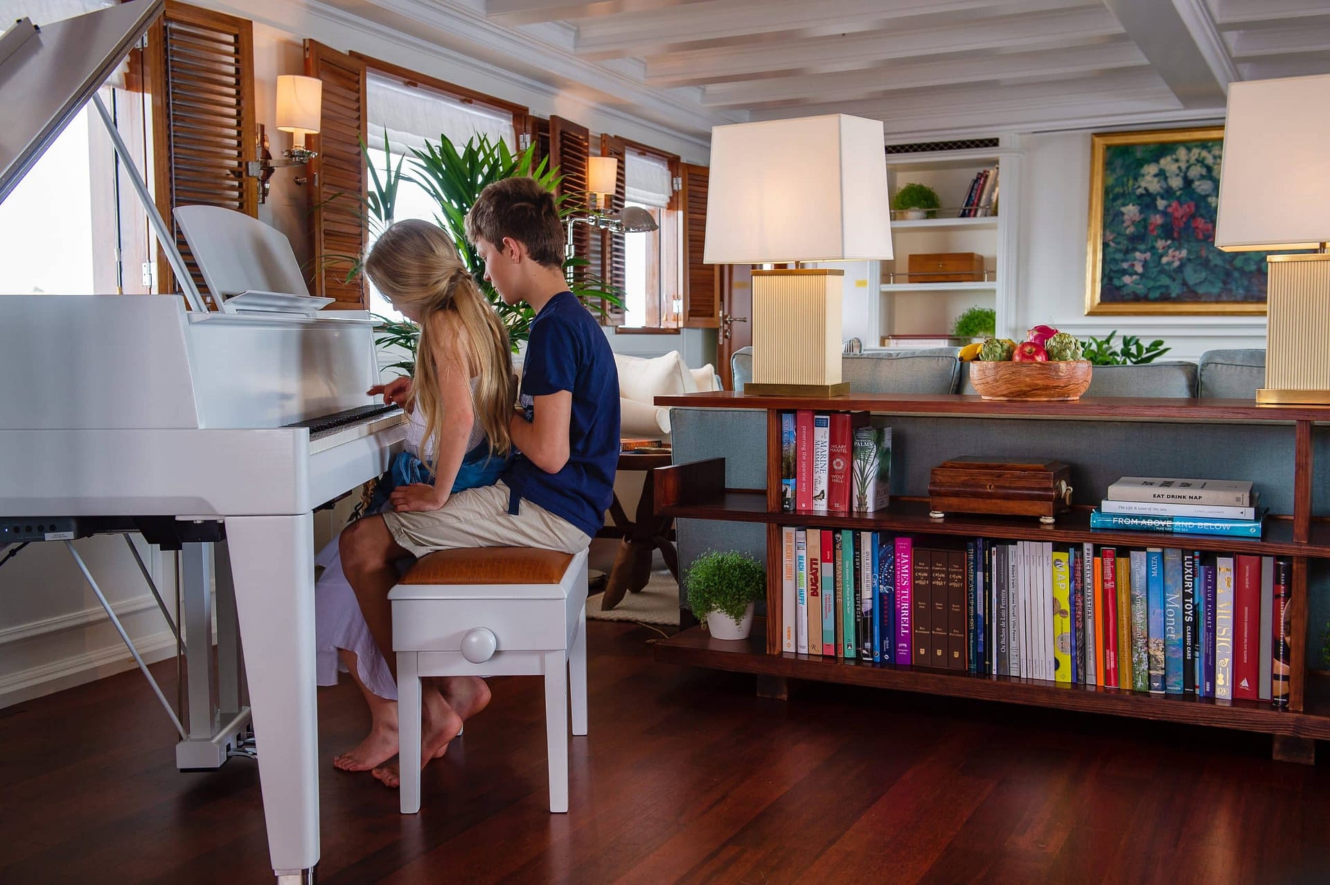 Two kids playing piano on a family yacht charter in the Mediterranean