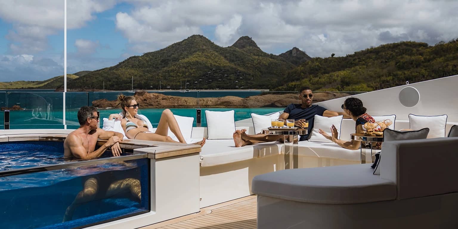 A group of people sitting on the deck of a yacht charter with a hot tub
