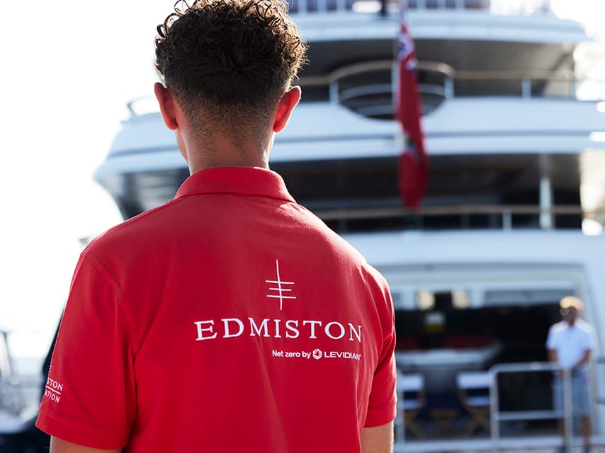 Man in Edmiston shirt next to a yacht at the palm beach international boat show