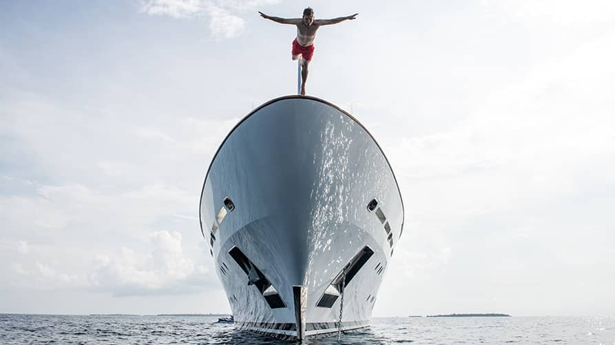 Person diving off the bow of a luxury superyacht