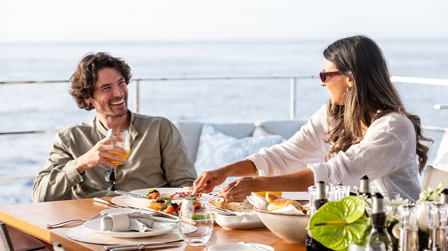 A couple enjoying their superyacht lifestyle with a champagne breakfast on deck.